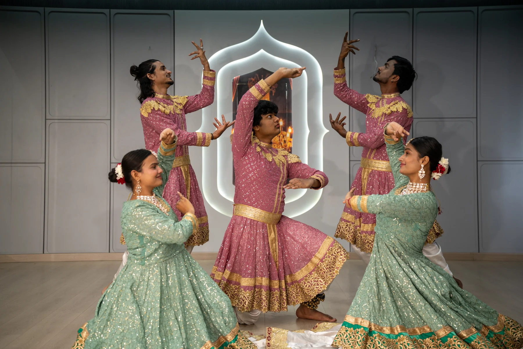 Kathak ensemble holding expressive poses in pink and green costumes