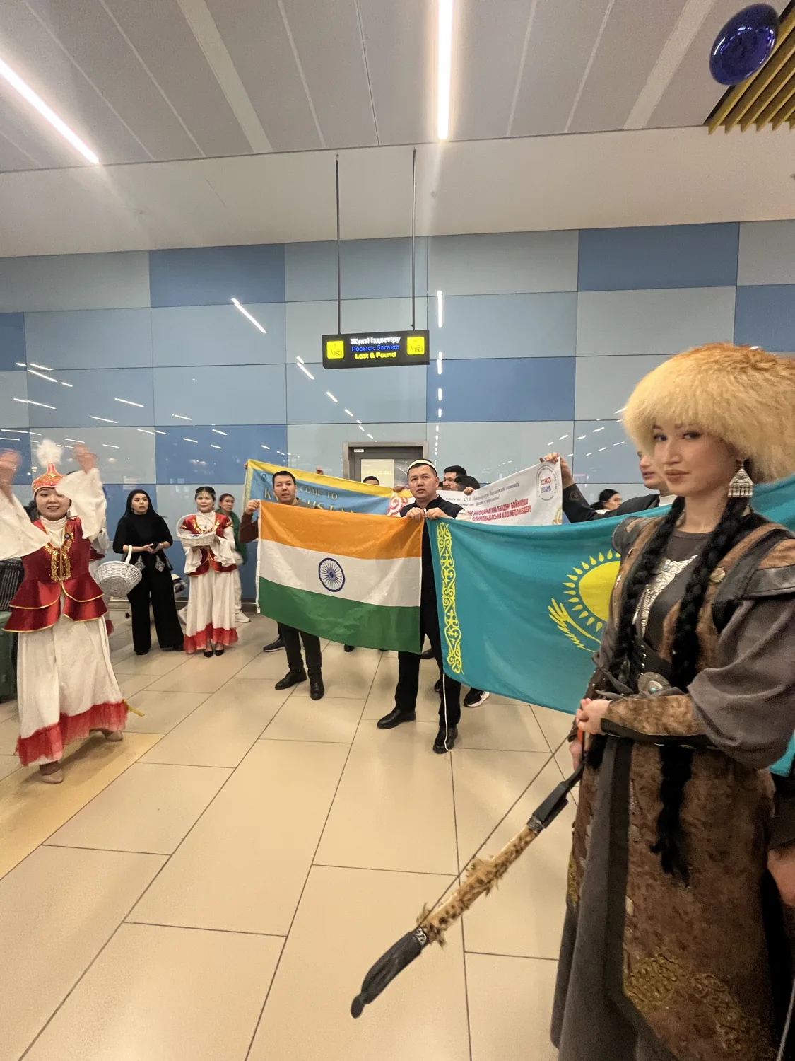 A group holding Indian and Kazakh flags at an airport